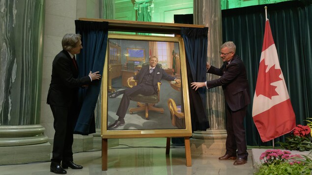 Le peintre Phil Richards (à gauche) et l'ancien premier ministre de la Saskatchewan, Brad Wall (à droite), dévoilent le portrait officiel de Brad Wall au Palais législatif de Regina le 30 novembre 2022.