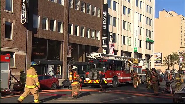 Des pompiers s'affairent à éteindre l'incendie sur le toit du bâtiment qui abrite le journal. Des pompiers s'affairent à éteindre l'incendie sur le toit du bâtiment qui abrite le journal.