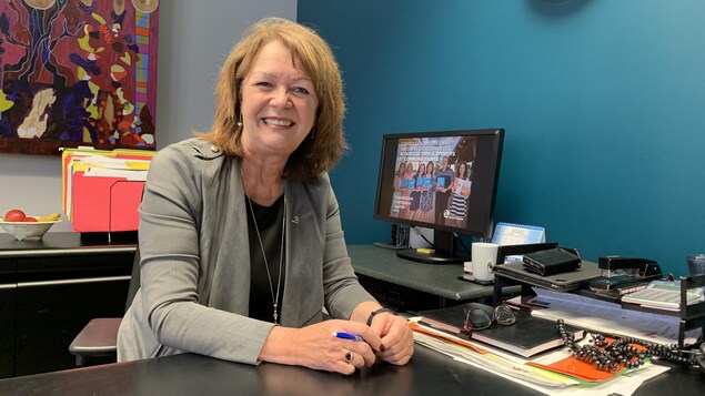 Diane Dallaire pose derrière son bureau, souriante.
