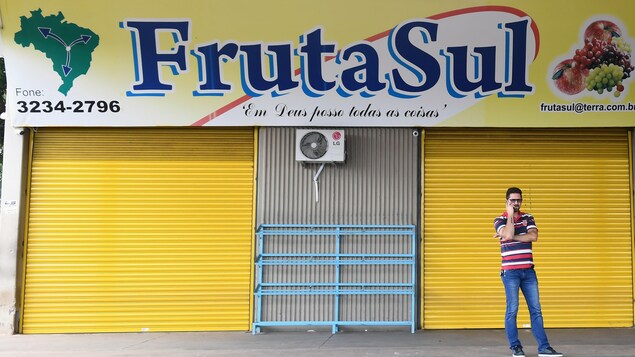 Un homme téléphone devant un magasin fermé à la devanture jaune, Un homme téléphone devant un magasin fermé à la devanture jaune,