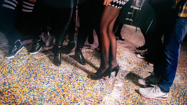 Pieds de gens avec des confettis au sol.