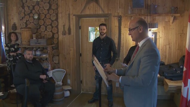 Rémi Massé est derrière un lutrin et s'adresse à des gens assis devant lui Rémi Massé est derrière un lutrin et s'adresse à des gens assis devant lui