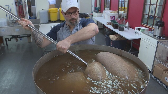 Un distilleur brasse le liquide dans une cuve.