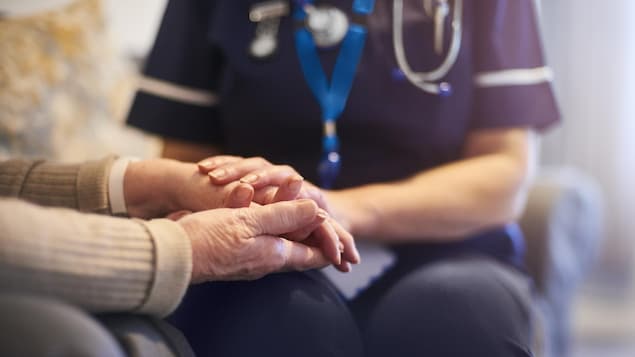 Une infirmière tient la main d'un aîné.