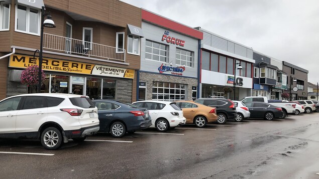 Quelques voitures sont stationnées sur une rue commerciale.