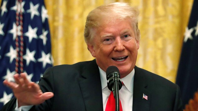 Le président Donald Trump bouge les bras.