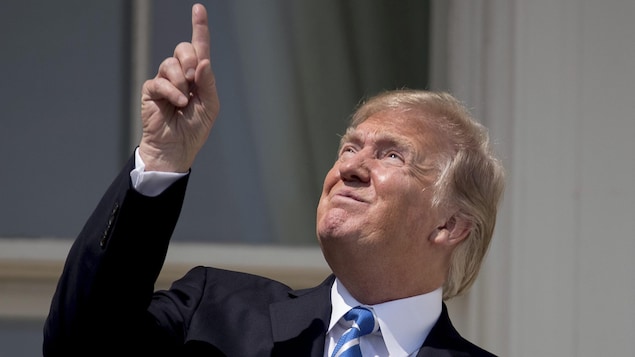 Le président américain Donald Trump pointe le ciel avant de revêtir des lunettes spéciales pour regarder l’éclipse lundi le 21 août 207 à la Maison Blanche à Washington.