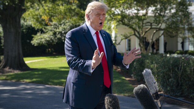 Donald Trump parle devant des micros tendus sur le terrain de la Maison-Blanche.