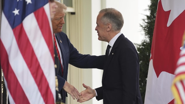 Mark Carney serre la main de Donald Trump, caché derrière un drapeau américain.