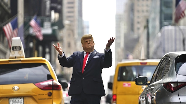 Un homme porte un masque représentant Donald Trump dans une rue de New York.