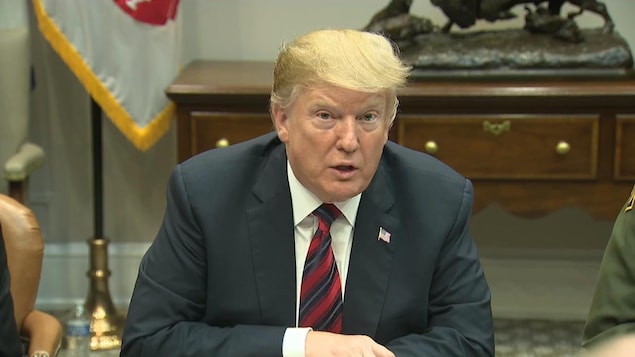 Donald Trump, assis, s'adresse à la caméra lors d'un point de presse.