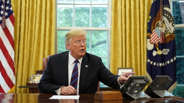 Trump compose un numéro sur son téléphone pendant qu'il est assis dans le bureau ovale à la Maison-Blanche.
