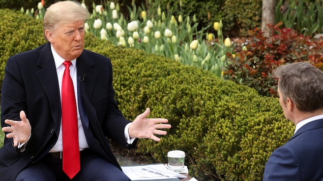 Donald Trump, assis sur un banc, s'adresse à un journaliste vu de dos.