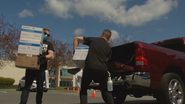 Deux hommes déchargent des boîtes de donations d'une camionette.