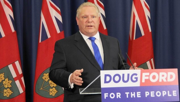 Doug Ford se tient derrière un podium et devant des drapeaux de l'Ontario