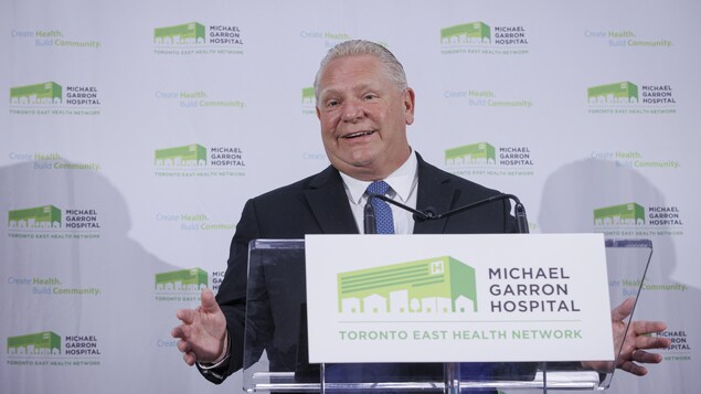 Doug Ford, les bras ouverts, derrière un lutrin.