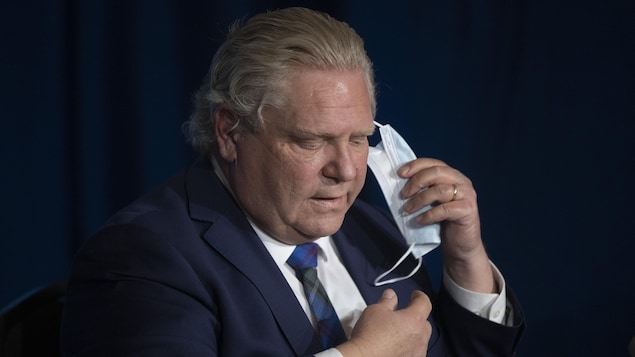 Le premier ministre ontarien, Doug Ford, enlève son masque avant un point de presse.