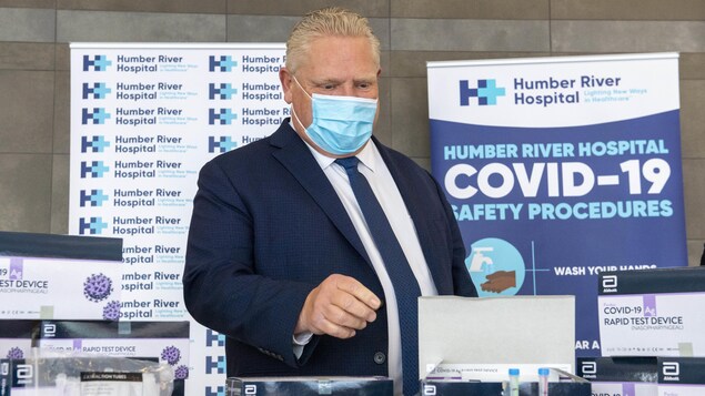 Doug Ford examine des trousses de test de dépistage rapide de la COVID-19.