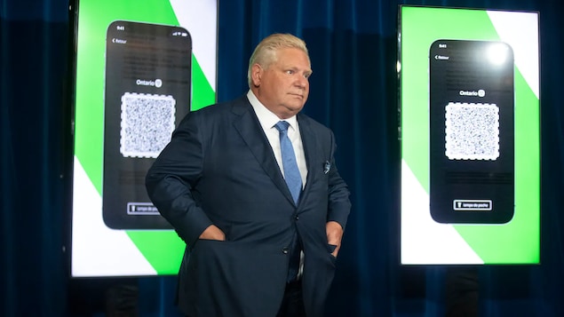 Nasa entablado si Doug Ford at nasa likod niya ang screen na nagpapakita ng vaccine verification app ng Ontario.