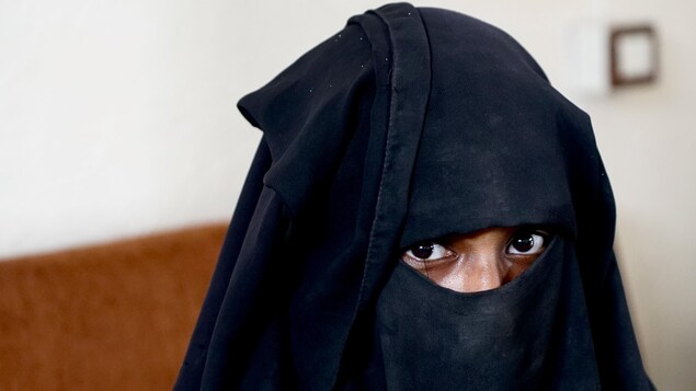 Une femme portant le niqab fixe la caméra.