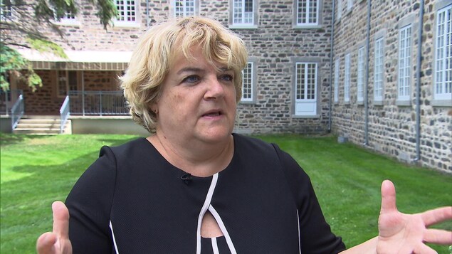 Annick Murphy est debout devant un édifice durant une entrevue.