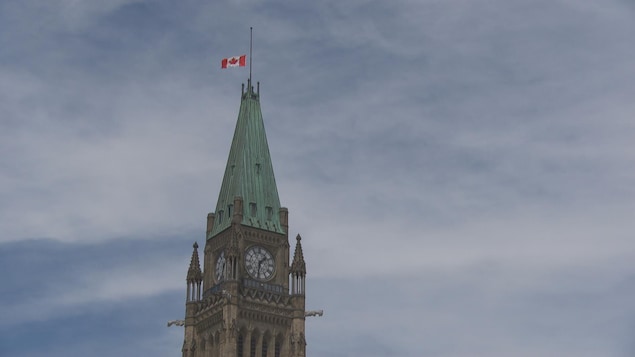 Una bandera canadiense a media altura en el edificio del Parlamento de Canadá.
