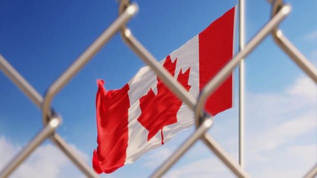 Le drapeau canadien visible derrière un grillage.