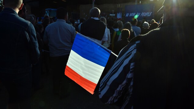 Un homme tient dans ses mains un drapeau de la France.
