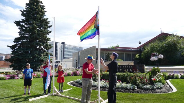 Des manifestants hissent deux drapeaux LGBTQ+.