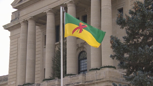 Un drapeau vert, jaune décoré par le ruban rouge, symbole de la lutte contre le sida, flotte devant le Palais législatif de la Saskatchewan. 
