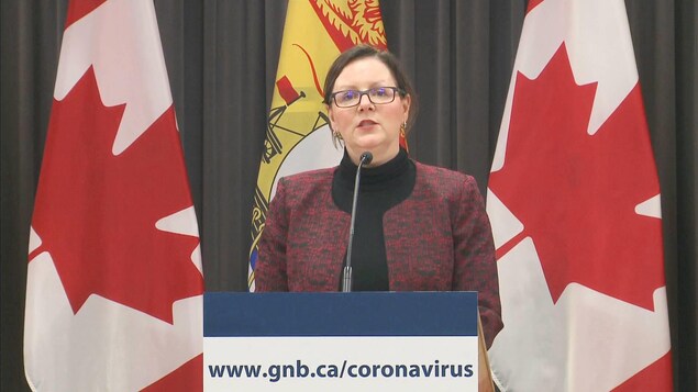 Jennifer Russell à un lutrin devant des drapeaux.
