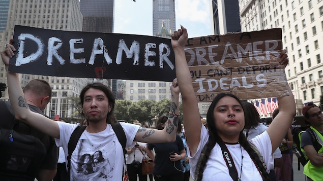 Deux jeunes tiennent des pancartes sur lesquelles sont écrites des slogans en faveur des Dreamers.