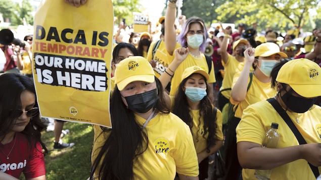 Des jeunes portant des chandails jaunes lèvent le poing et brandissent des pancartes.