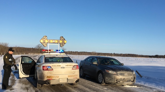 Une voiture de police avec un panneau d'arrêt illuminé.