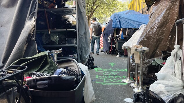 Un homme se faufile entre des tentes de sans-abris sur un trottoir du quartier du Downtown Eastside à Vancouver.