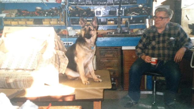 Un homme est assis dans un atelier avec son chien. Un homme est assis dans un atelier avec son chien.