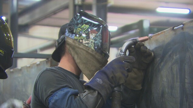 Un ouvrier effectue de la soudure protégé d'un masque.
