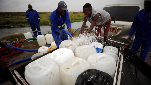 Des Africains pompent de l'eau dans des rÃ©servoirs. 