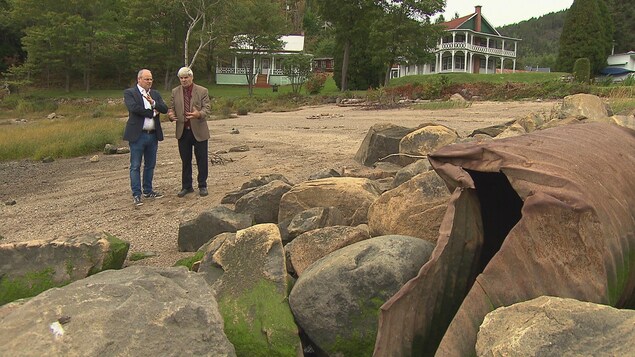 Le maire et un journaliste regardent au loin un vieux tuyaux près de deux maisons. Le maire et un journaliste regardent au loin un vieux tuyaux près de deux maisons.