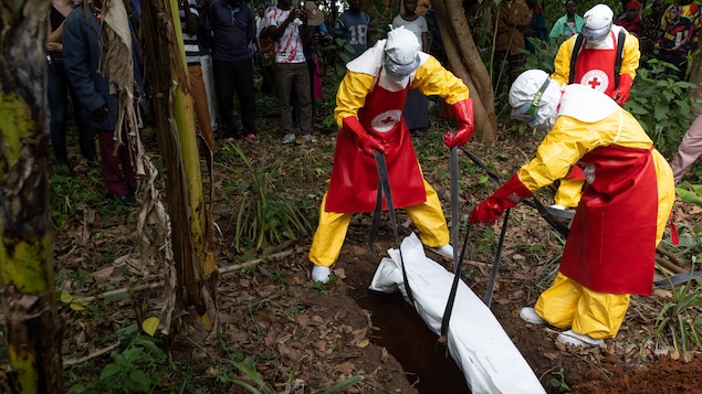 Des agents de la Croix-Rouge déposent un sac mortuaire, contenant le corps d'un enfant de 3 ans soupçonné d'être victime du virus Ebola, dans une tombe.