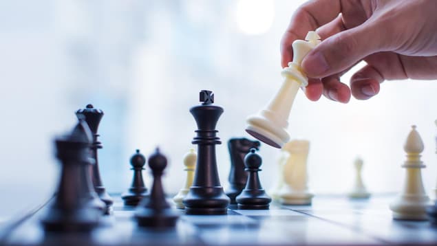 Une main bouge le roi dans un jeu d'échecs