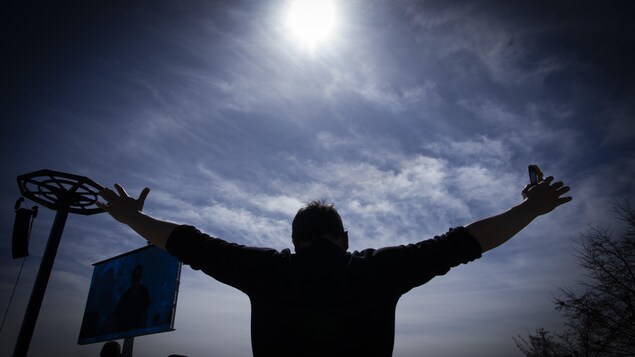  
Un homme tend les bras vers le ciel pendant l'éclipse totale du Soleil.
