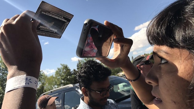 Une femme regarde l'éclipse solaire à travers son téléphine cellulaire. Une femme regarde l'éclipse solaire à travers son téléphine cellulaire.