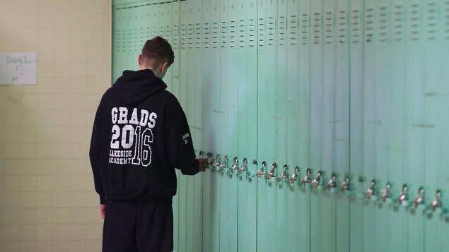 Un étudiant à son casier. Il porte un chandail à l'effigie de son école, Lakeside Academy, dans l'arrondissement de Lachine.