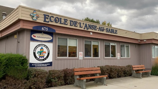 Le bâtiment de l'École de l'Anse-au-sable devant lequel se trouve deux bancs en bois.
