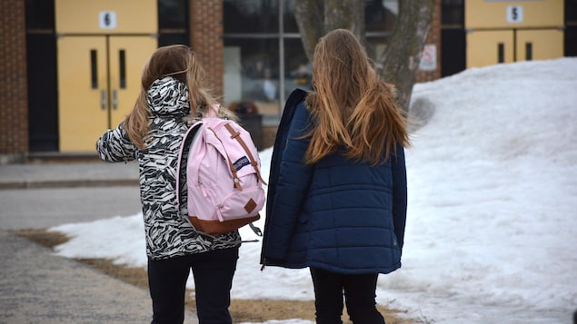 Deux élèves s'apprêtent à entrer dans l'école.