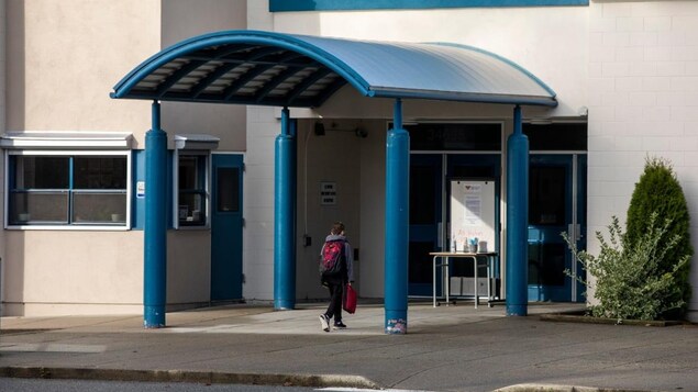 Un élève marche vers l'entrée principale d'une école.