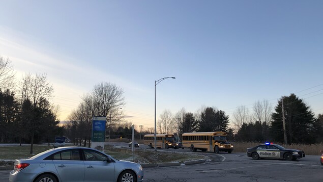 Des autobus scolaires escortés par une voiture de police.