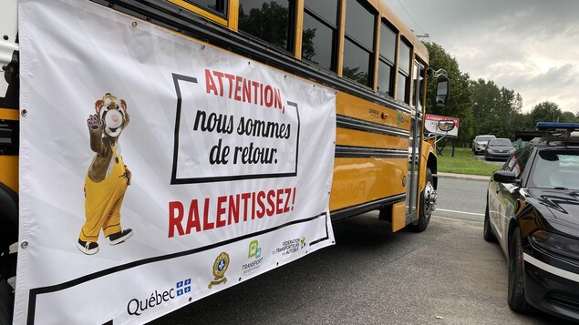 Une banderole avec le slogan « Attention, nous sommes de retour. Ralentissez! », installée sur un autobus.
