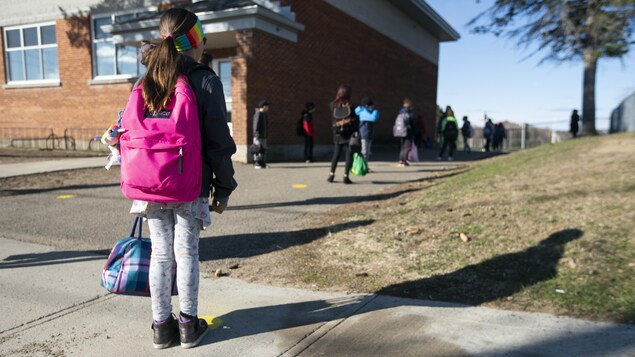 Des enfants gardent une bonne distance entre eux avant d'entrer dans une école.